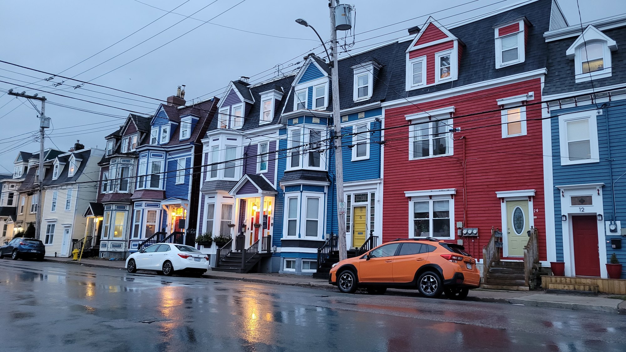 A row of brightly painted jellybean row houses on a rainy street in St. John's, Newfoundland