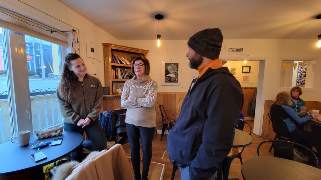 Yannick explaining his hike across Canada to Pier-Ann and her student at the Battery Café